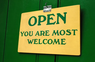 polite old welcome sign hanging in a doorway