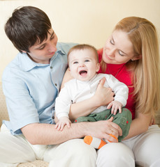 Young happy family sitting on sofa at home