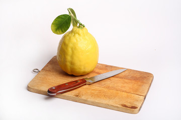 One lemon with knife on the board