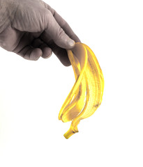 Man's hand holding a bright yellow banana skin.