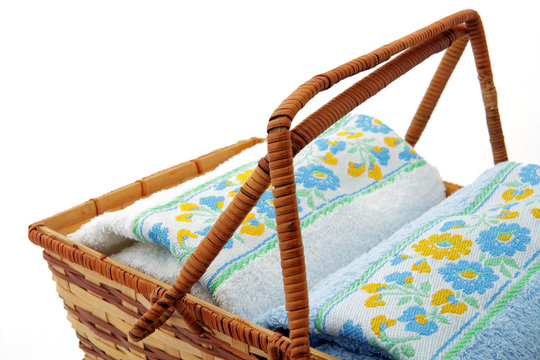 Two rolled up towels with flower decoration in wicker basket