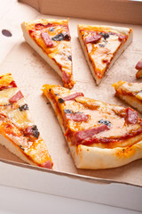 sliced ham and cheese pizza in a cardboard pizza-box