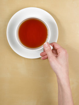 tea - female hand holds a cup of tea on wood table