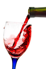 Red wine flowing from a green bottle to a glass, clipping path