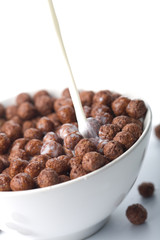 milk pouring into bowl with chocolate balls isolated