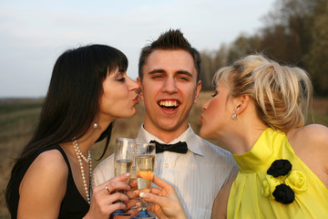 surprise - two girl with wine kissing man outdoors