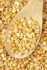 Background of split dried pea and wooden spoon