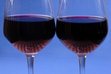 Close up of two red wine glasses. Blue background.