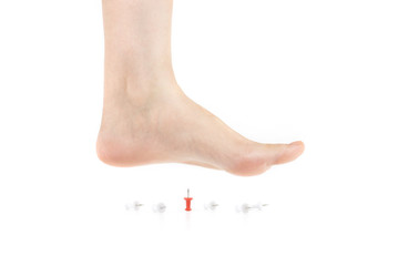 Side view of bare foot stepping on the pushpins