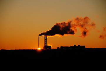 Siluate of a factory at the end of the day.