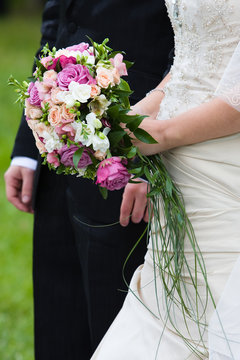 Bride and groom stand near each other with wedding flowers