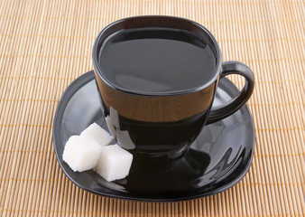 Sugar and black cup of coffee on wooden background