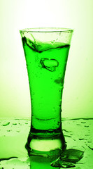 Glass with green beverage and ice