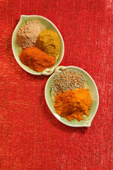 piles of indian powder spice on two plates red glitter backgrou