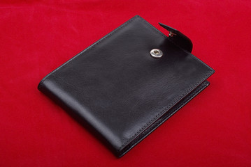 Black leather wallet isolated on the red background. Studio shot