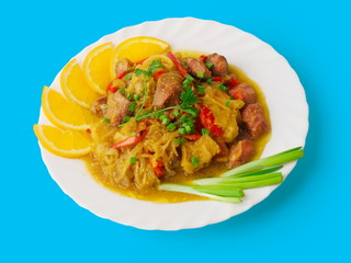 Meat goulash with cabbage, orange and pepper on blue
