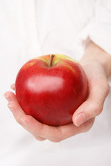 Young female hand holding red apple
