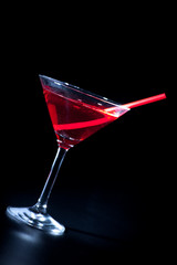 Schöner roter Cocktail mit Trinkhalm vor schwarz