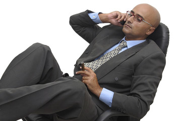 Businessman at the phone sitting on a chair
