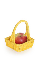 Big apple inside yellow wicker basket isolated on white