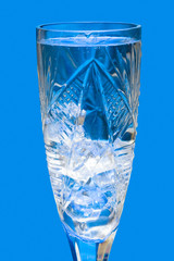 Glass with water and ice over blue