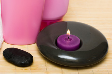 Fototapeta na wymiar Pink bottle of shampoo with candle and pebble
