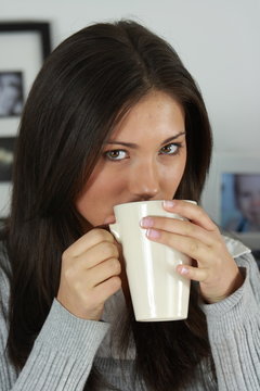 Young woman with beautiful face is having her tea/coffee