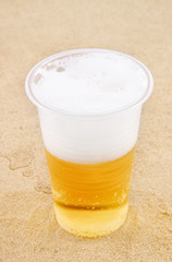 Glass of fresh beer on desert sand