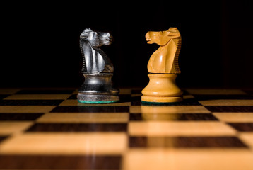 Two chess knights fight on chessboard © Gordon Saunders