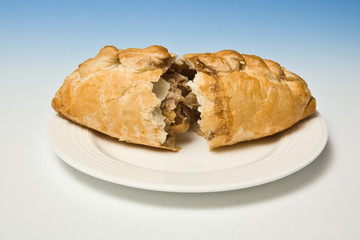 Cornish pasty isolated on a graduated blue studio background.