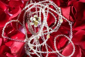 Shiny jewelry over red rose petals