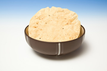 bowl of Pappadums on a blue studio background