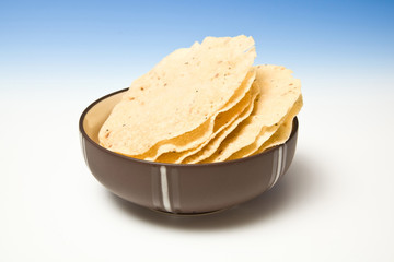 bowl of Pappadoms on a blue studio background.