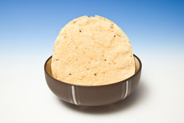 bowl of Pappadums on a blue studio background.