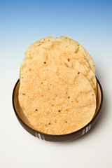 bowl of Pappadums on a blue studio background.