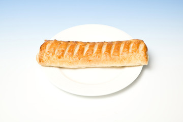 Jumbo sausage roll on a blue  studio background.