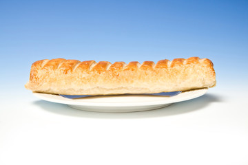 Jumbo sausage roll on a blue  studio background.