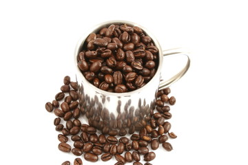 steel cup full of coffee beans close up isolated in studio