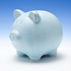 Piggy bank style money box on a blue studio background.
