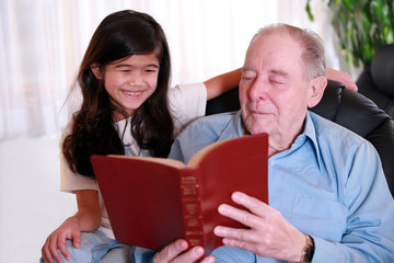 Elderly man and little girl reading Bible together