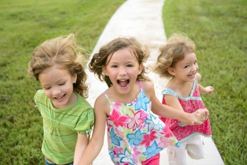 Fototapeta premium Three sister girls playing running on the park