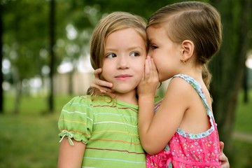 Two twin little sister girls whisper in ear - obrazy, fototapety, plakaty