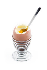 An eggcup with an open egg and teaspoon in it.