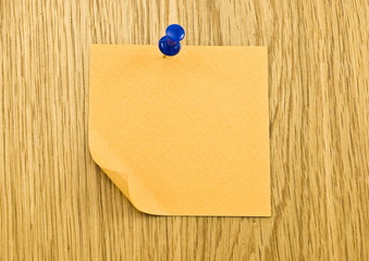 Single orange blank note paper attached to a wooden wall