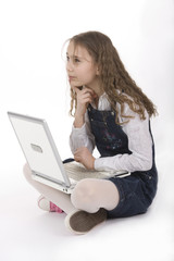 Adorable school girl sitting on floor with laptop computer