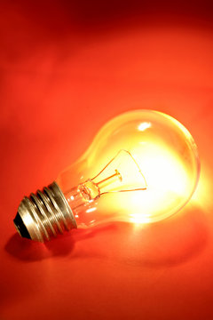 Light bulb glowing on red background