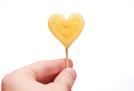 Hand gives heart-shaped candy isolated