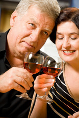 Elderly happy couple celebrating with red wine at home
