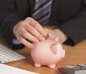 Business man putting money in Piggy bank