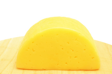Piece of cheese on wooden plate.